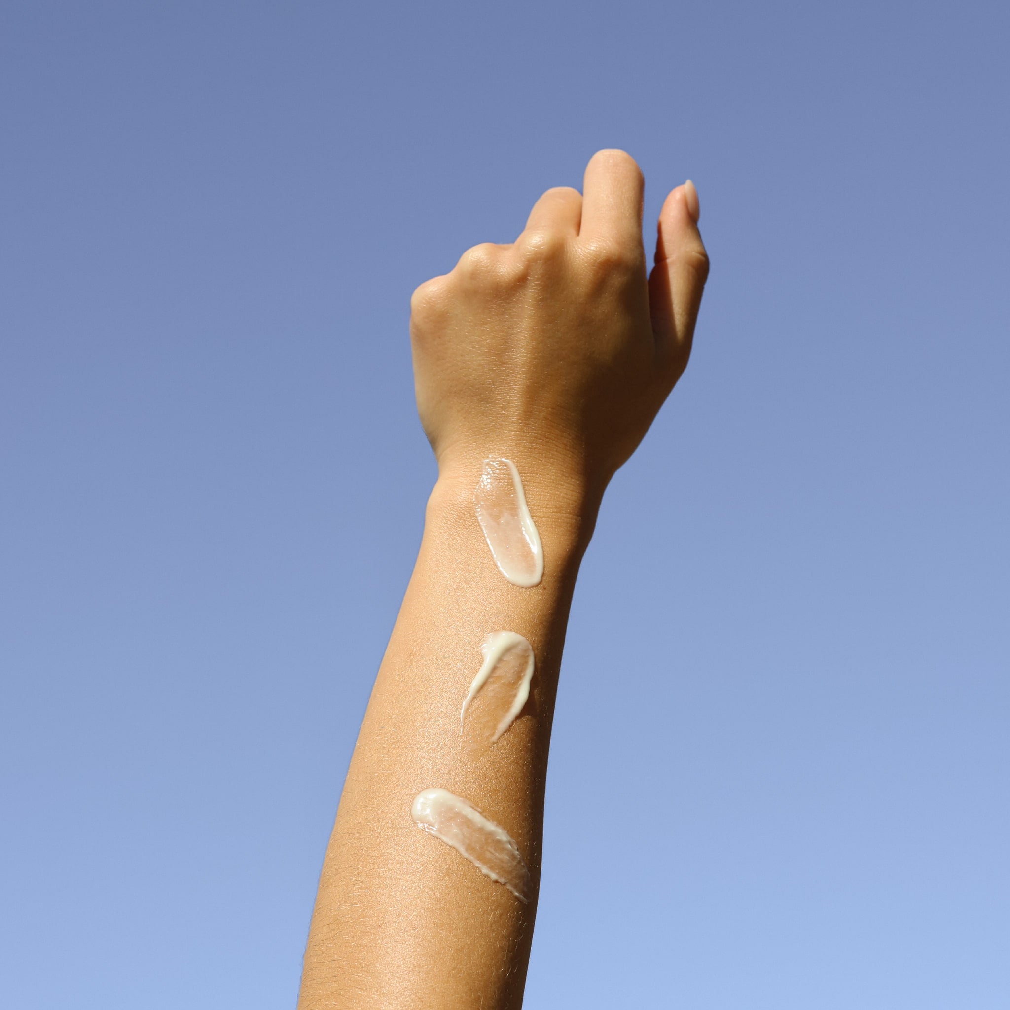 A close-up of a person's forearm showing three swatches of Eco By Sonya Body Milk moisturiser.