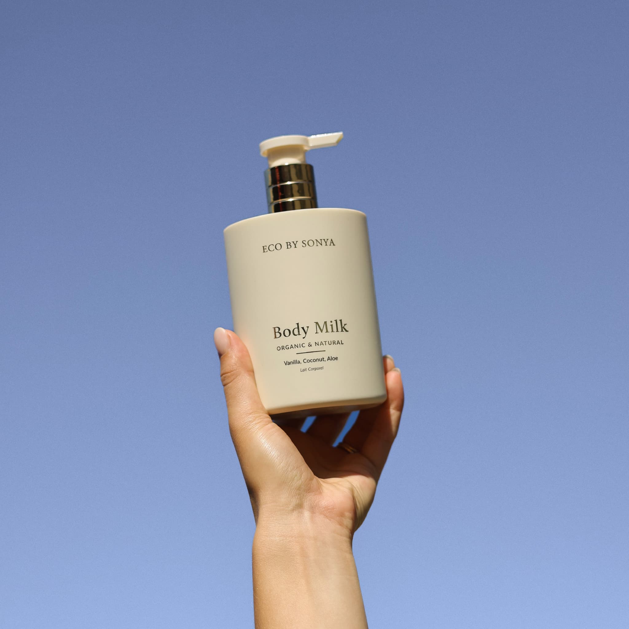 A hand holding Eco By Sonya Body Milk hydrating lotion.