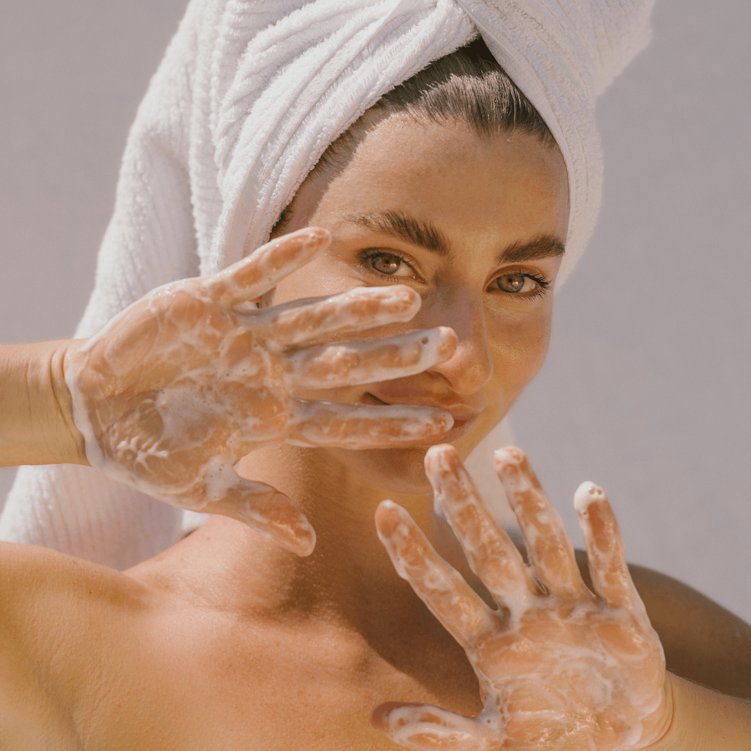 Woman with a towel wrapped around her head, holding soapy hands up to her face using Super Citrus Cleanser